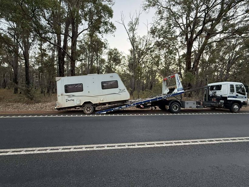 Pop-top caravan being towed by the tilt tray on a highway