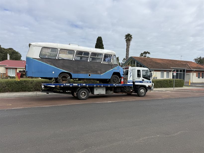 Vintage blue and white bus carried on the tilt tray through town