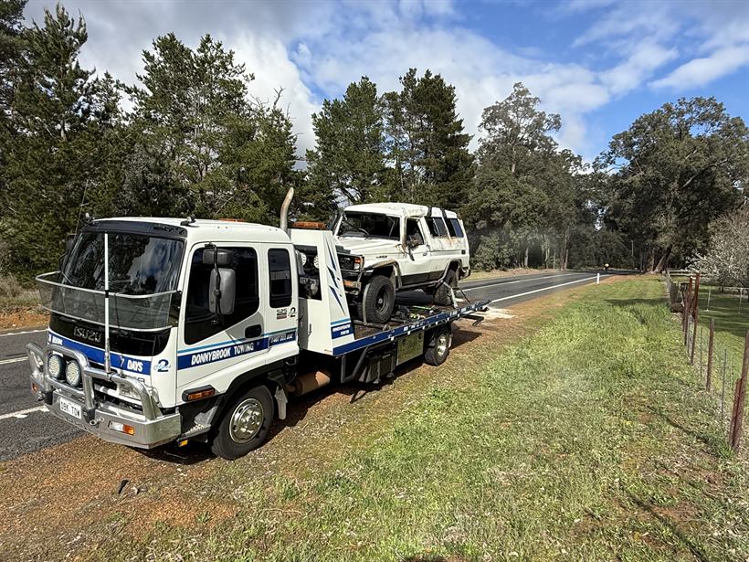 Rolled white LandCruiser Troopy loaded on the Donnybrook Towing tilt tray beside a country road